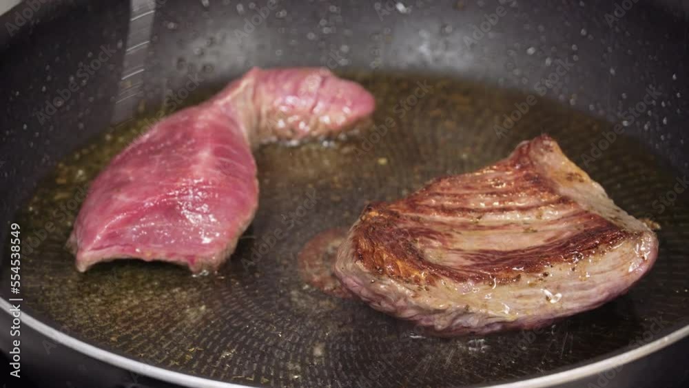 Top sirloin marbled American beef steak flipped on a pan. Selective high-angle close focus on cooking meat with olive oil. Top sirloin marbled American beef steak flipped on a pan. Selective high-angle close focus on cooking meat with olive oil.