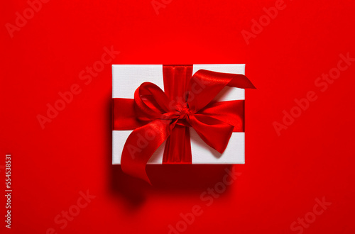 Gift card. Gift box with ribbon bow red  background © LiliGraphie