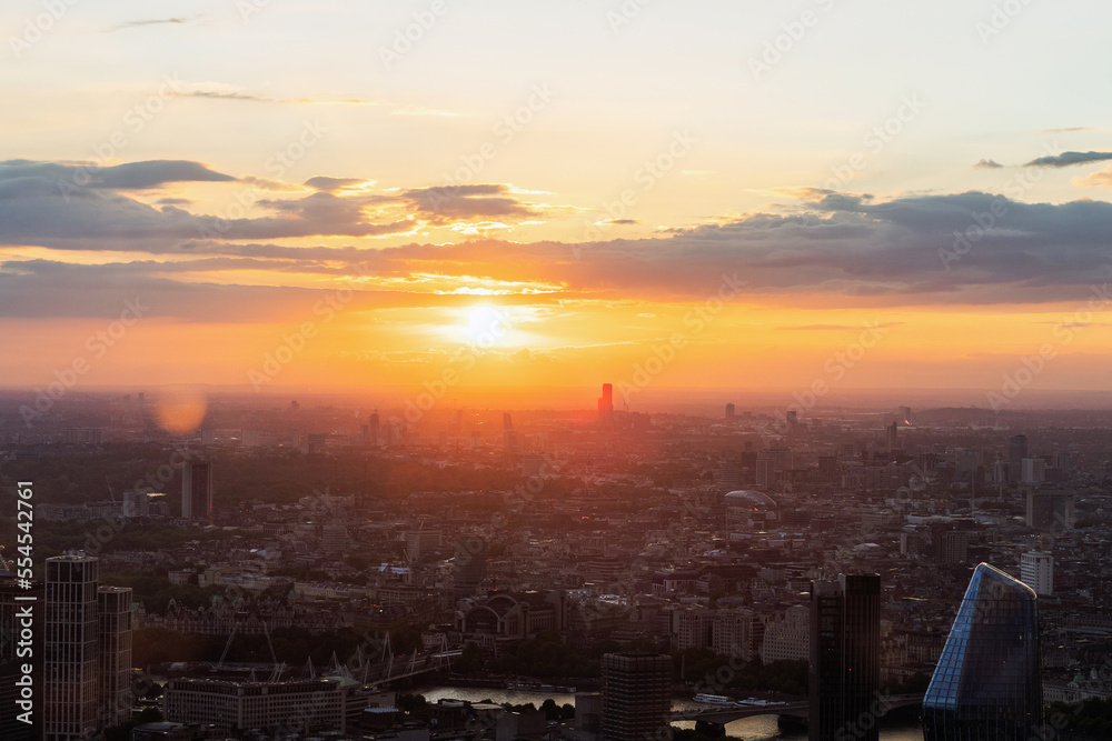 Panoramic view of London city skyline illuminated by colorful sunset light, aerial shot. Famous landmark buildings and architectural attractions on the river banks.