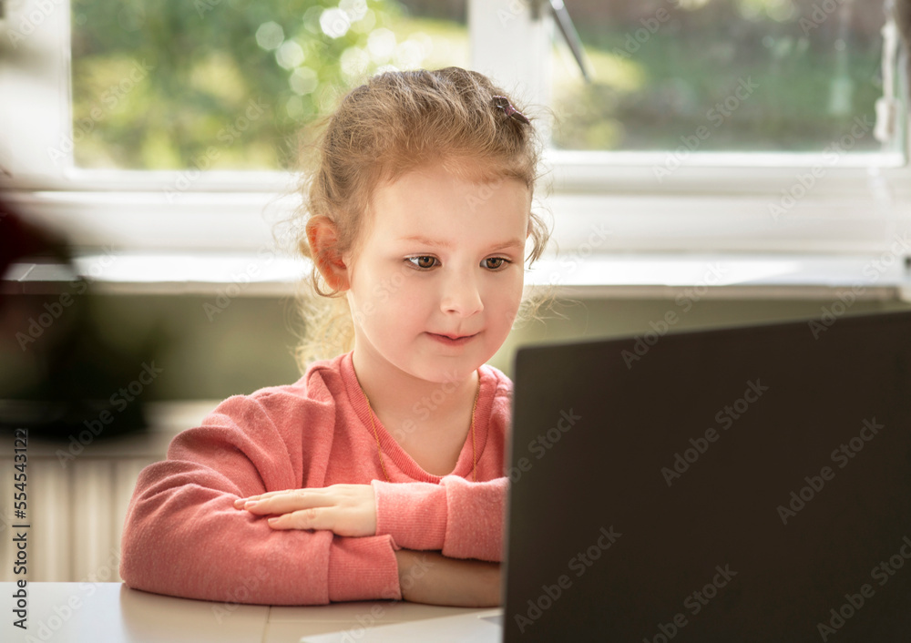 a young girl kid studying online. Child sitting working on computer laptop. online education. studying from home a young girl kid studying online. Child sitting working on computer laptop. online education. studying from home