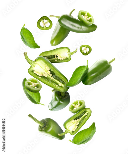 Flying green jalapeno peppers and fresh basil leaves on white background photo