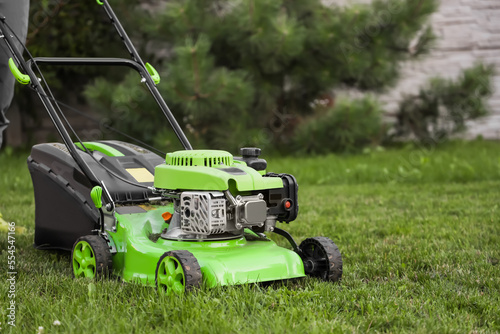 Modern lawn mower on green grass