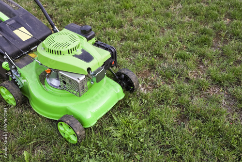Modern lawn mower on fresh green grass