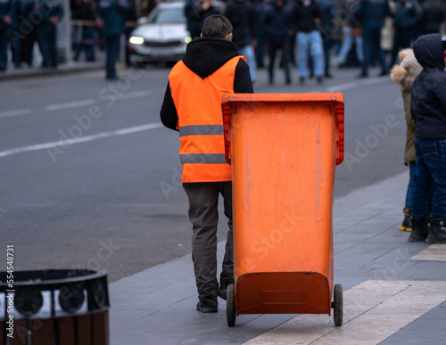 City cleaner dragging a trash can