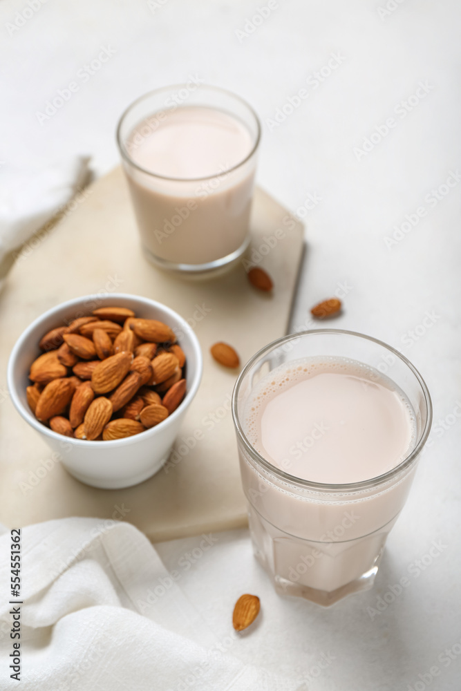 Board with glasses of healthy almond milk and nuts on light background Board with glasses of healthy almond milk and nuts on light background