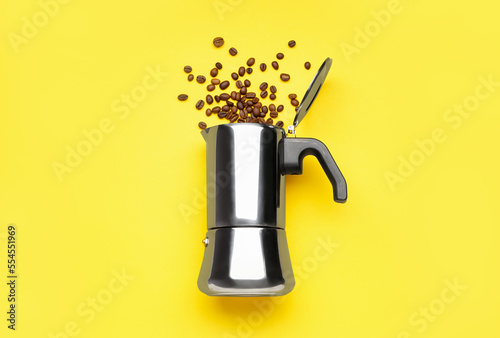 Geyser coffee maker with scattered beans on yellow background