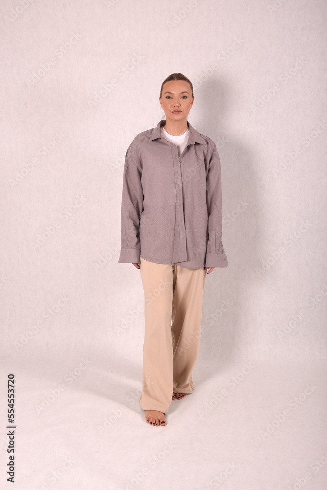 A young girl in beige home clothes on a white background in the studio A young girl in beige home clothes on a white background in the studio