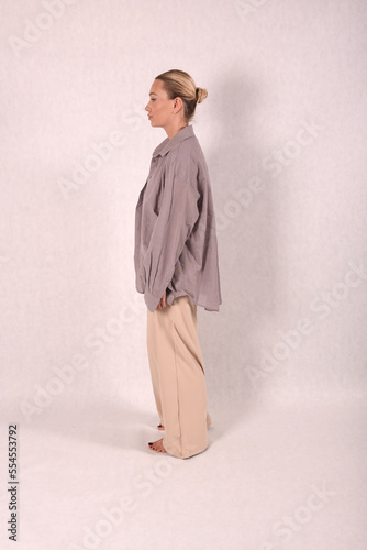A young girl in beige home clothes on a white background in the studio