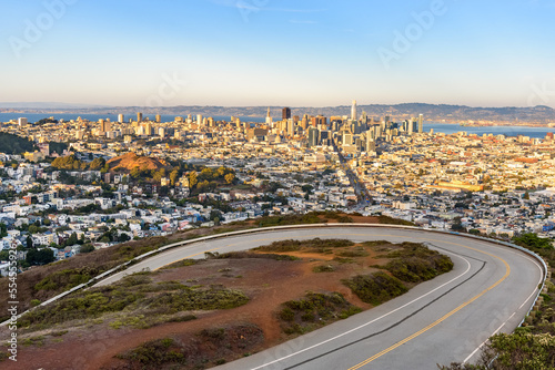 Elevated view of San Francisco downtown at sunset in autumn. A winding road is in foreground.