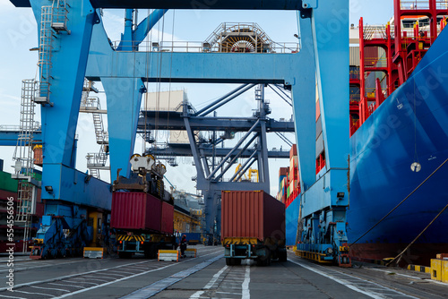 Container port with container ship. berthing crane loads container onto the ship. Tractors at port terminal
