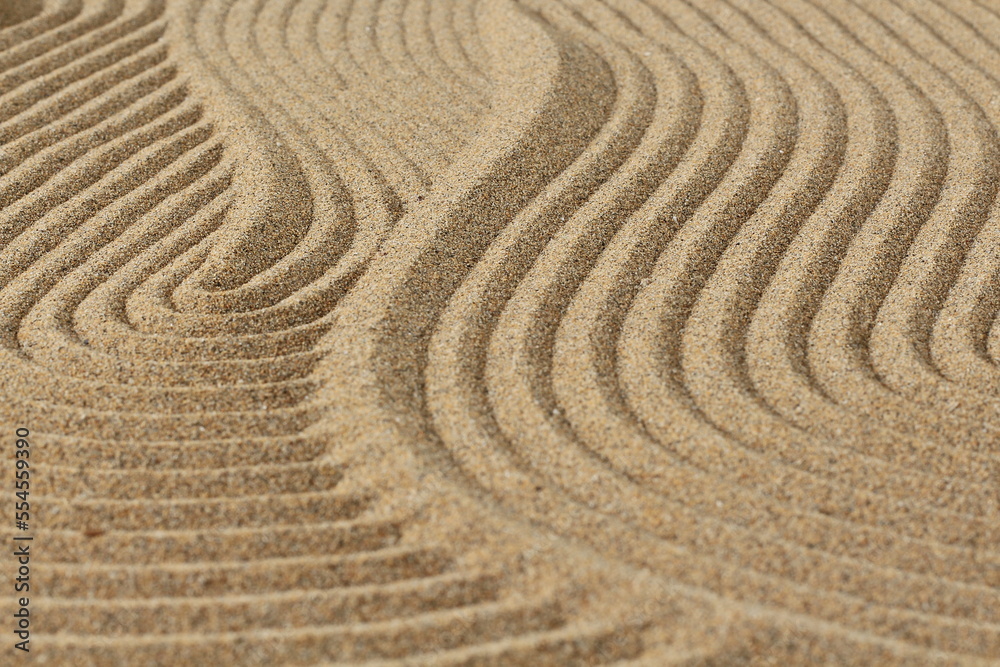 Naklejka premium Zen garden, abstract drawing of waves on the sand, the concept of harmony, balance and meditation, spa, massage, relaxation, sand texture background, wallpaper, shallow depth of field,