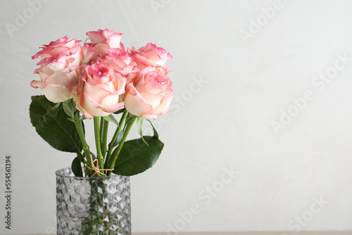 Fototapeta Naklejka Na Ścianę i Meble -  Vase with beautiful pink roses on light grey background, closeup. Space for text