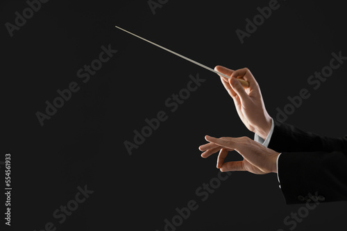 Fototapete Professional conductor with baton on black background, closeup