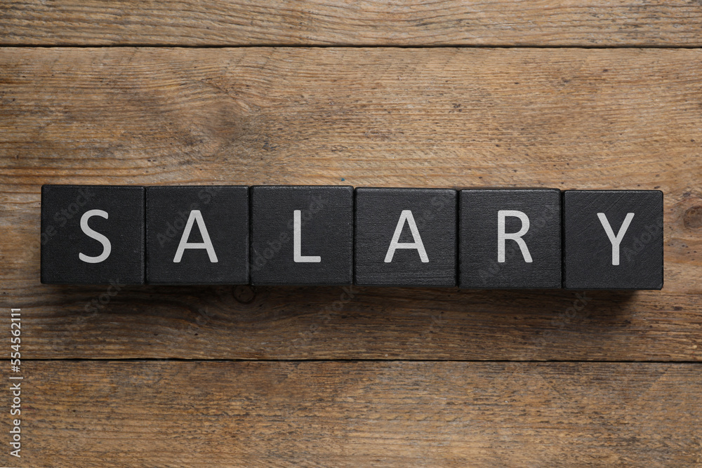 Word Salary made with black cubes on wooden table, flat lay Word Salary made with black cubes on wooden table, flat lay
