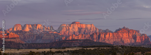 West Temple, Mt. Kinesava and the surrounding mountains of Zion National park Utah, USA, glow red and orange in the light of the setting sun, as seen from Smith Mesa on a chilly winter evening.