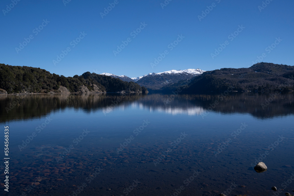 Alpine landscape in summer. Panorama view of the calm lake, forest and volcano Batea Mahuida, under a deep blue sky. Beautiful environment reflection in the water surface. Alpine landscape in summer. Panorama view of the calm lake, forest and volcano Batea Mahuida, under a deep blue sky. Beautiful environment reflection in the water surface.