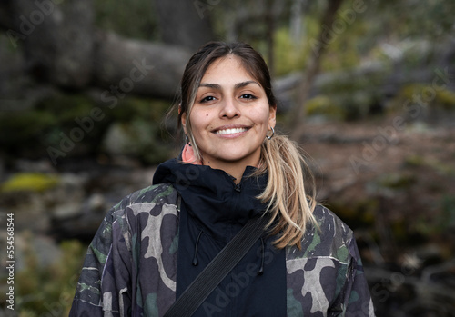 Hiking in the woods. Portrait of a smiling young woman in her 20s, in the forest.