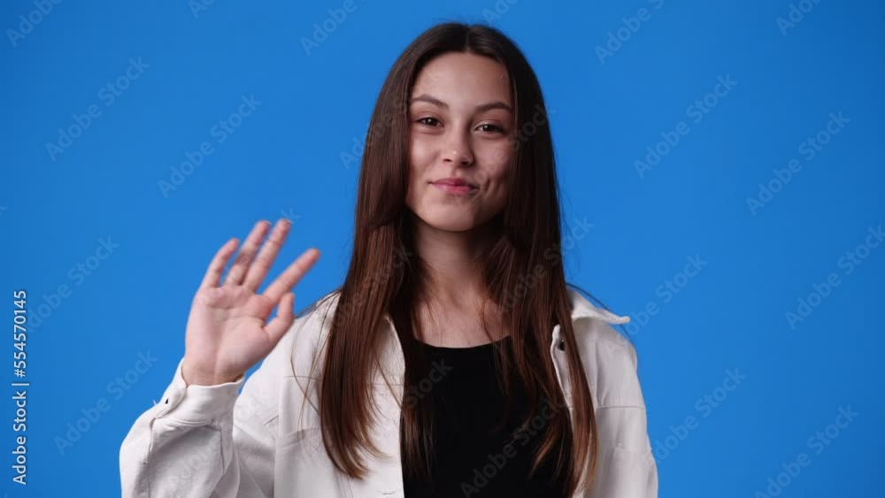 4k slow motion video of cute girl waving hello on blue background. 4k slow motion video of cute girl waving hello on blue background.
