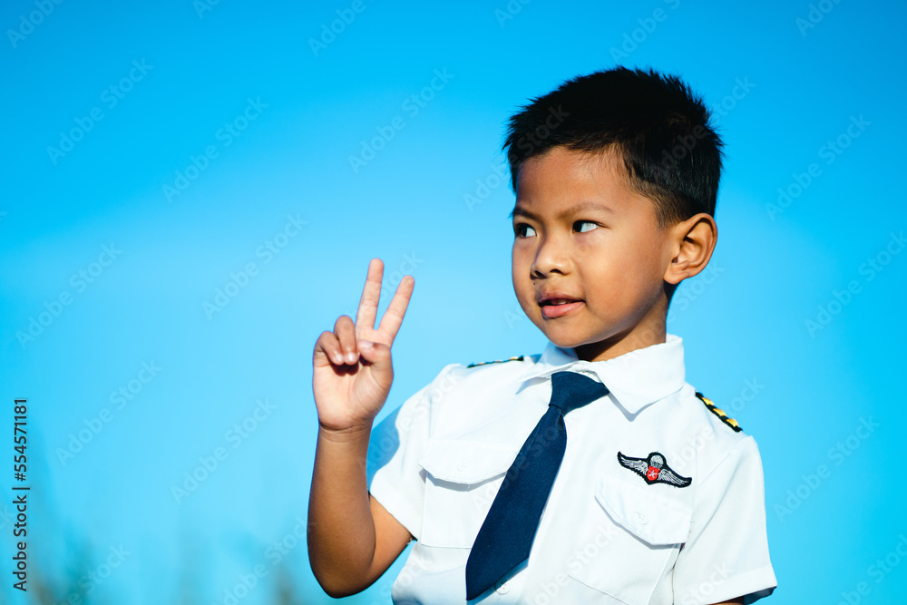 Boy standing with thumbs up in white flight suit on blue background Boy standing with thumbs up in white flight suit on blue background