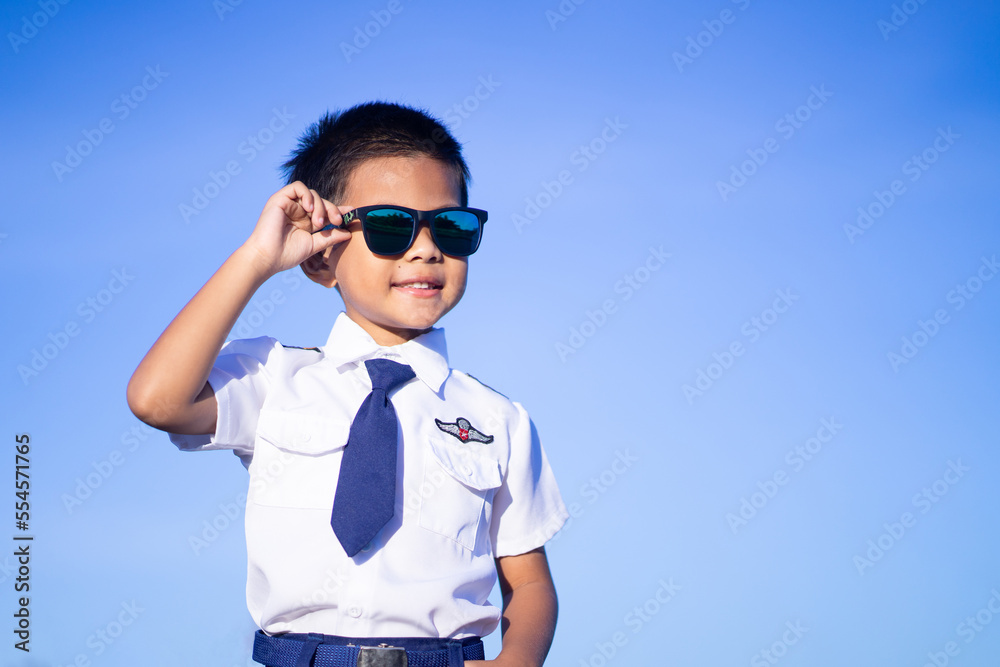 A boy wearing black glasses wearing a pilot suit on a blue background A boy wearing black glasses wearing a pilot suit on a blue background