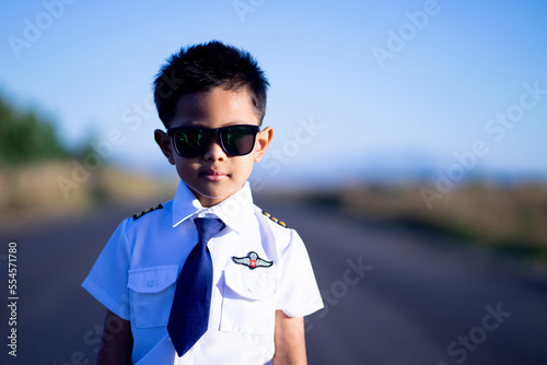 A boy with dark glasses wearing a pilot's suit has a sharp look