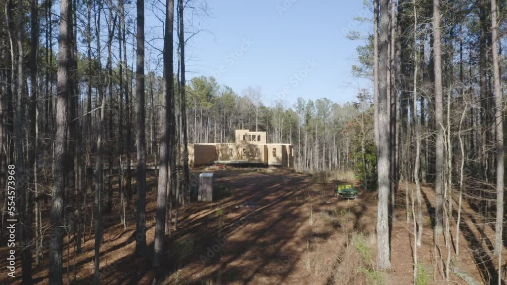 Flying closer towards house under construction in woods Flying closer towards house under construction in woods