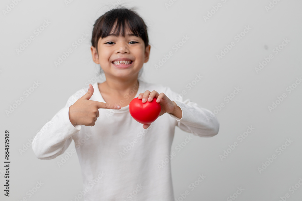 Portrait of Asian little girl child holding red heart sign on white background Portrait of Asian little girl child holding red heart sign on white background