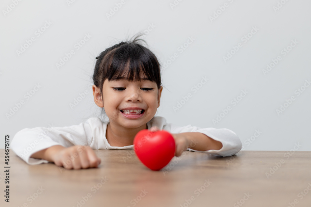 Portrait of Asian little girl child holding red heart sign on white background Portrait of Asian little girl child holding red heart sign on white background