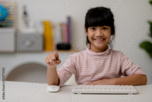 education, school, and imaginary screen concept - Asian little girl pointing in the air or imaginary screen