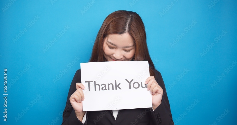 Asian business woman holding paper the text Thank You with happy smile face in sale advertising and copy space Asian business woman holding paper the text Thank You with happy smile face in sale advertising and copy space