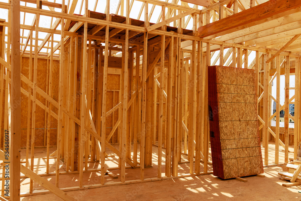 A house under construction is framed with beams. A house under construction is framed with beams.