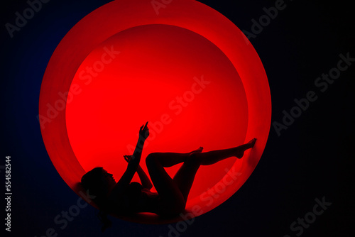 Silhouette of a young girl in red fill with beautiful legs and arms