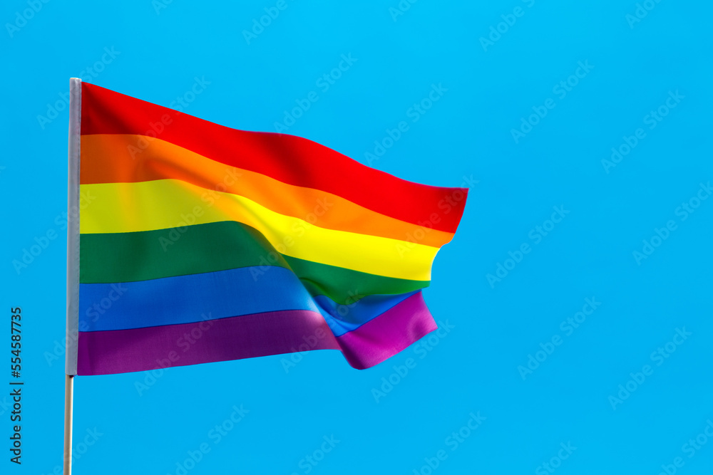Rainbow flag waving on blue background Rainbow flag waving on blue background