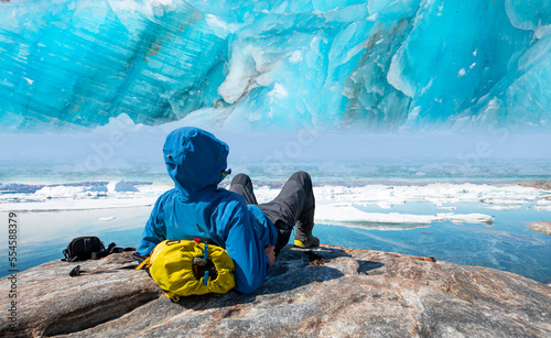 Hiker looking at melting glacier - Melting of a iceberg and pouring water into the sea - Greenland - Tiniteqilaaq, Sermilik Fjord, East Greenland