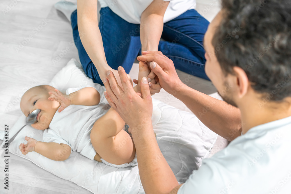 family in the studio or at home crawling on the floor with a baby. mom, dad, son play together