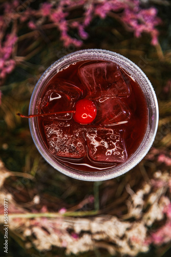 Red cherry lemonade with ice and cherries in a flower nest top view