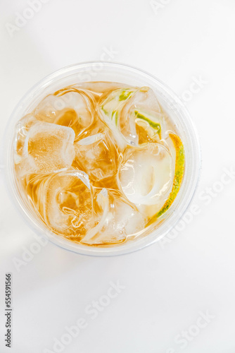 Classic lemonade with ice and lime slices in a transparent glass on a white background. View from above