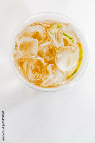Classic lemonade with ice and lime slices in a transparent glass on a white background. View from above