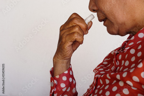 Closeup Asian woman use inhaler to smell for relieve dizzy or faint symptoms. Concept, health problem, sickness and remedy. Increases freshness, reduces dizziness and stuffy nose. self take care. 