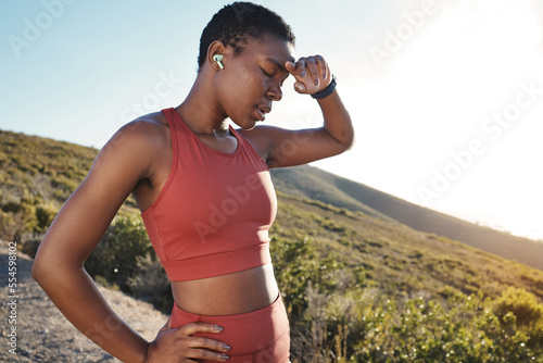 Fototapeta Naklejka Na Ścianę i Meble -  Fitness, music and tired with a sports black woman running in the mountain for cardio or endurance exercise. Workout, exhausted and sweat with a young female runner or athlete taking a break