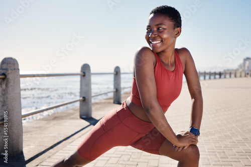 Stretching legs, happy and black woman training on the promenade for running, fitness exercise and health in Indonesia. Motivation, warm up and African athlete ready for an outdoor workout by the sea