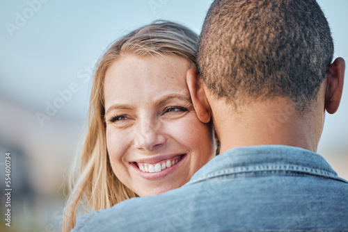 Couple, interracial with hug, love and travel, woman smile with black man, commitment and relationship with outdoor bonding. Face zoom, happy and romance in nature, trust and care with support.