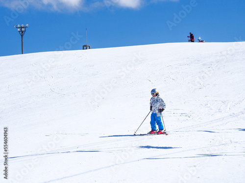 ゆるやかなゲレンデをスキーで滑る子供