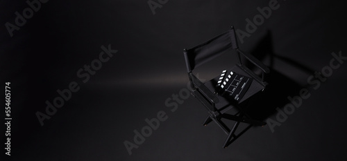 Black Director chair and clapper board on black background.