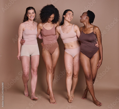 Beauty, skincare and diversity of women with hug and smile for health, wellness and confidence. Body care, natural and cosmetic model group in underwear for inclusive campaign at brown studio. photo