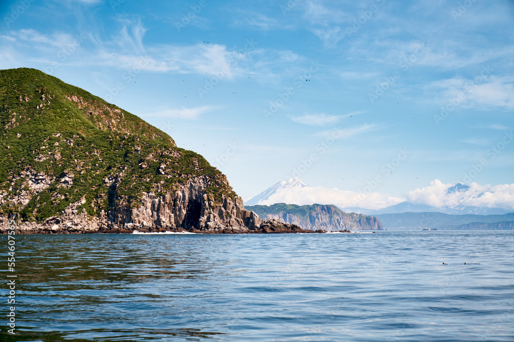 Summer landscape of the coastline with snow covered volcano. Kamchatka