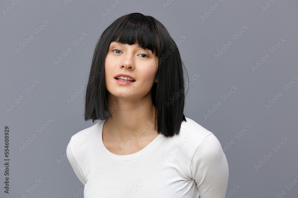 a relaxed woman stands full-face on a dark background in a white tight T-shirt, calmly stands with her hands behind her back a relaxed woman stands full-face on a dark background in a white tight T-shirt, calmly stands with her hands behind her back