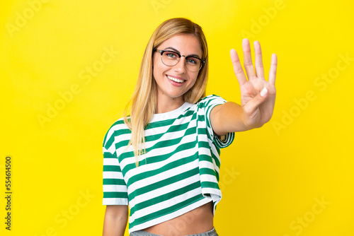 Blonde Uruguayan girl isolated on yellow background happy and counting four with fingers © luismolinero