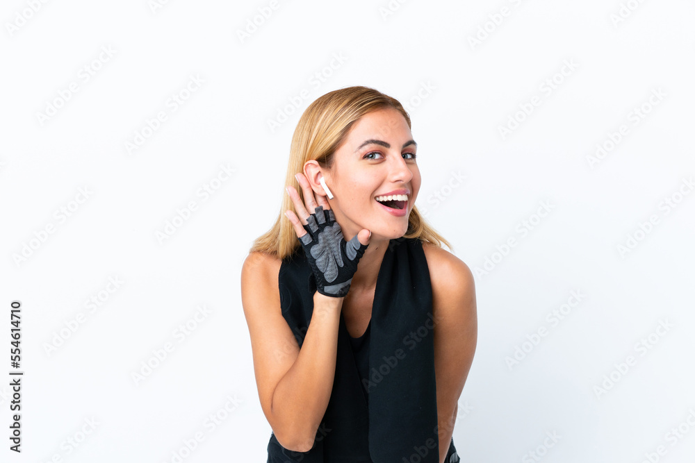 Blonde Uruguayan sport girl isolated on white background listening to something by putting hand on the ear Blonde Uruguayan sport girl isolated on white background listening to something by putting hand on the ear