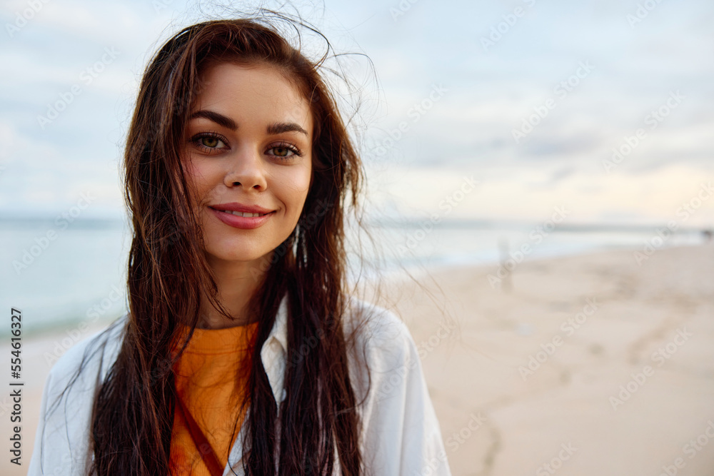 Portrait of a woman smile with teeth in a yellow tank top and white beach shirt with wet hair after swimming on the ocean beach sunset light